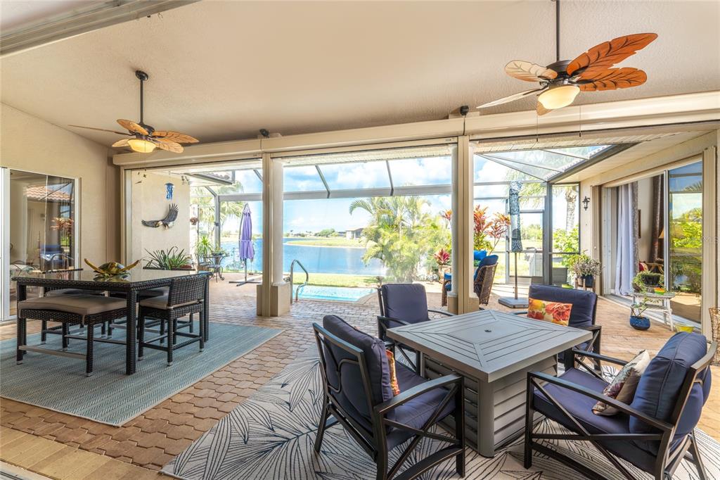 A covered patio features outdoor furniture, ceiling fans, and a screened view of a lake — 16237 CAPE HORN BOULEVARD, PUNTA GORDA, FL