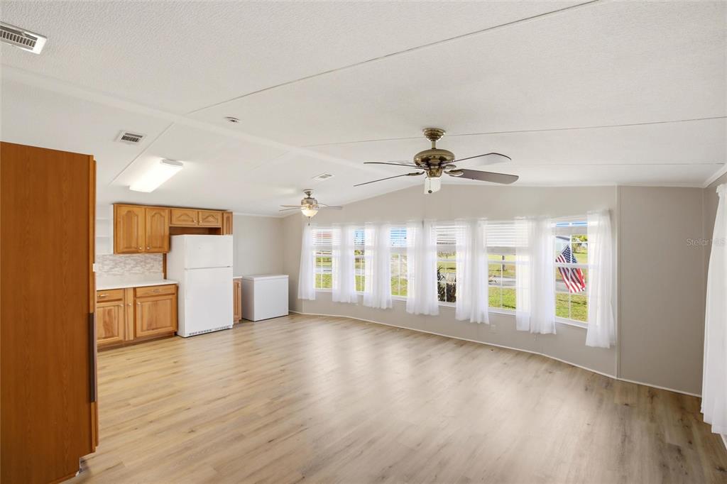 A living room with light wood flooring, a ceiling fan, and a kitchen area — 29215 EDGEWOOD STREET, PUNTA GORDA, FL