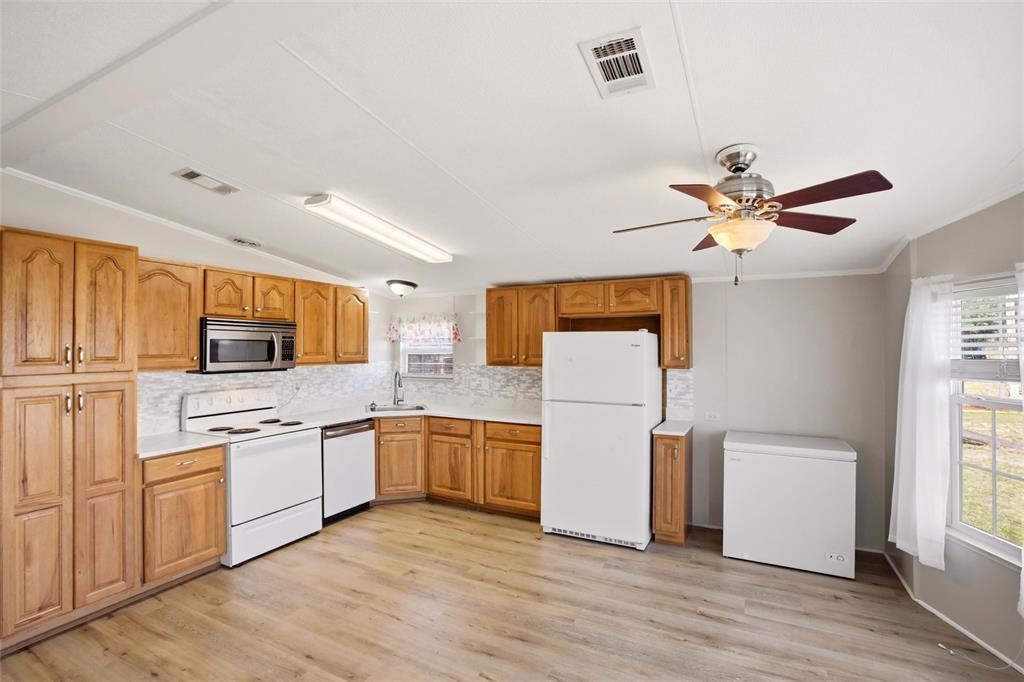 A kitchen with wood cabinets, white appliances, a ceiling fan, and light wood-look flooring — 29215 EDGEWOOD STREET, PUNTA GORDA, FL
