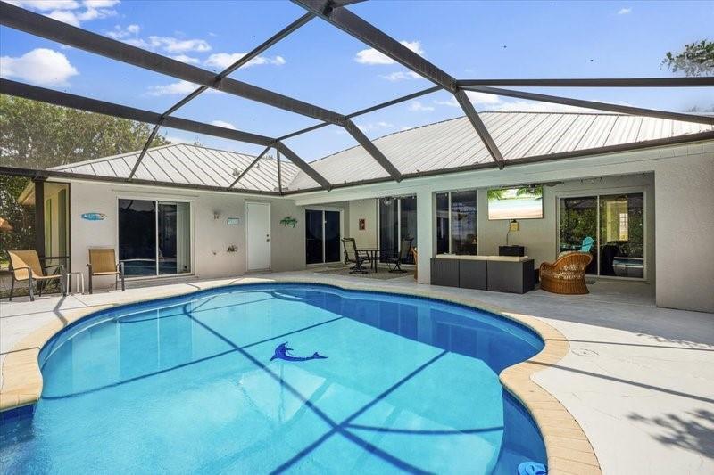 A swimming pool with a dolphin mosaic sits inside a screened-in patio area — PORT ST. LUCIE, FL