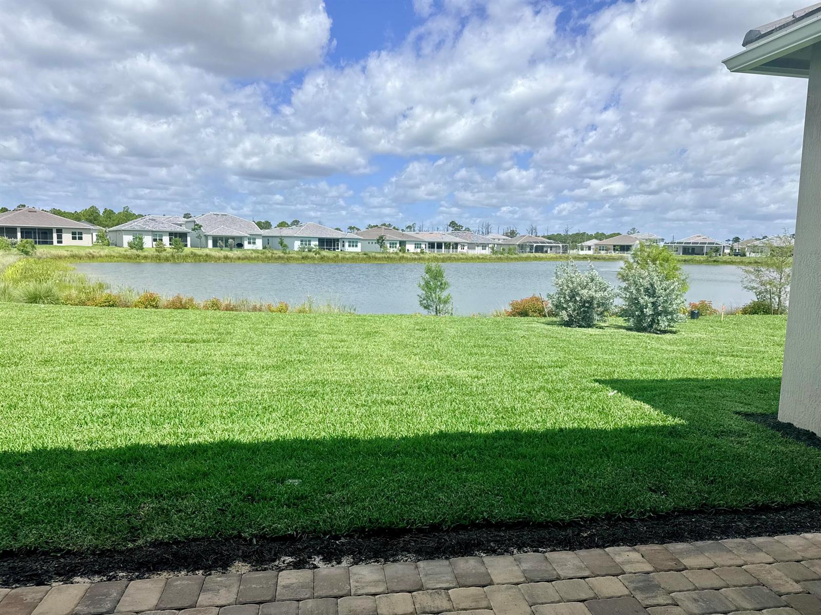 A view of a grassy backyard overlooking a lake with houses in the distance — 10470 SW Highpointe Drive # 127, Stuart FL 34997, STUART, FL