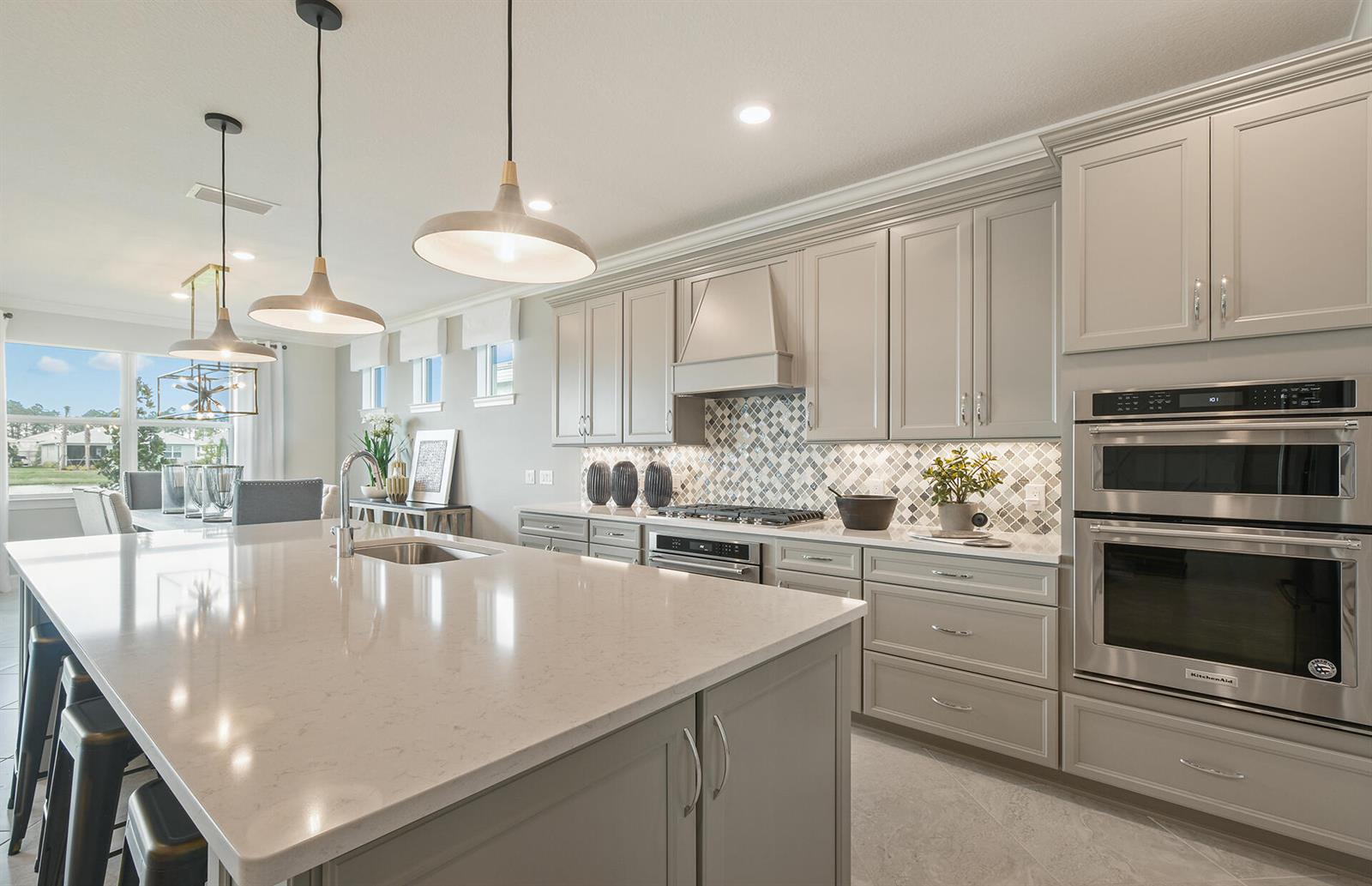 A modern kitchen features gray cabinetry, a large quartz island, and stainless steel appliances — 10470 SW Highpointe Drive # 127, Stuart FL 34997, STUART, FL