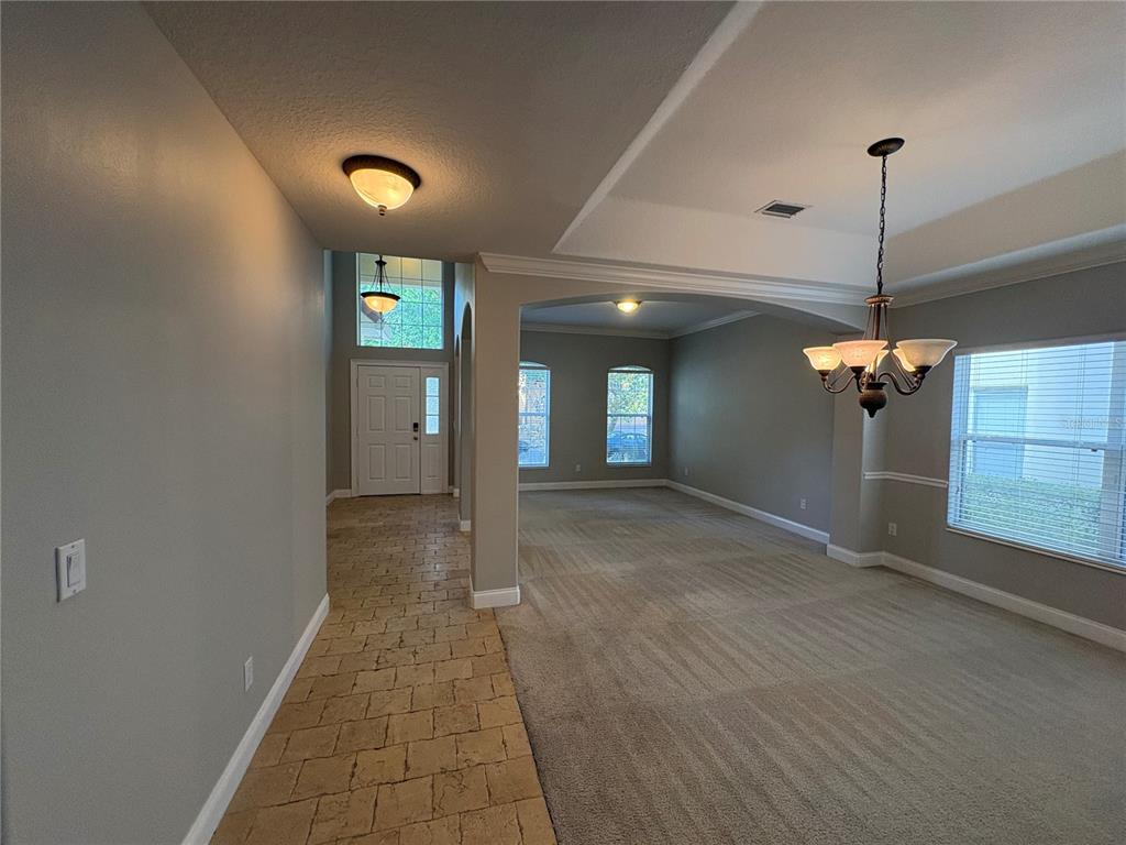 A view from a carpeted dining area toward a tiled entryway with a front door — 6931 LUCCA STREET, ORLANDO, FL