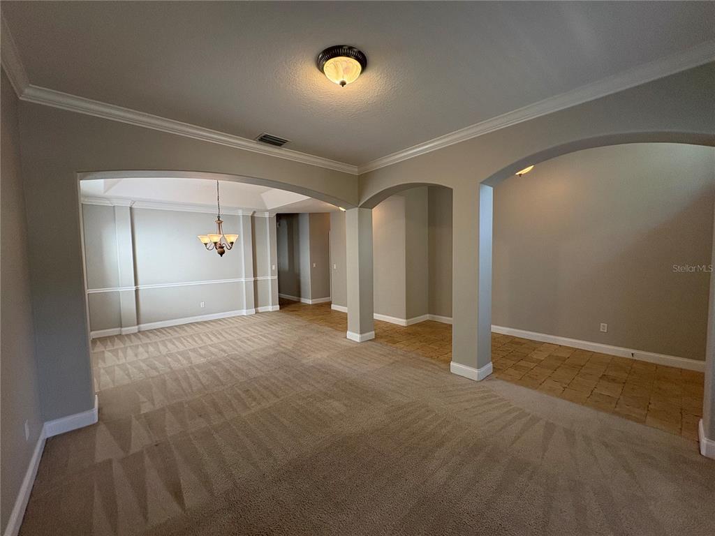 A carpeted living area features arched openings leading to a dining room and tiled space — 6931 LUCCA STREET, ORLANDO, FL