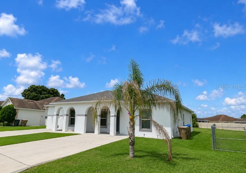 A white single-story house with arched entryways and a palm tree in the front yard — 828 ABBEVILLE COURT, KISSIMMEE, FL