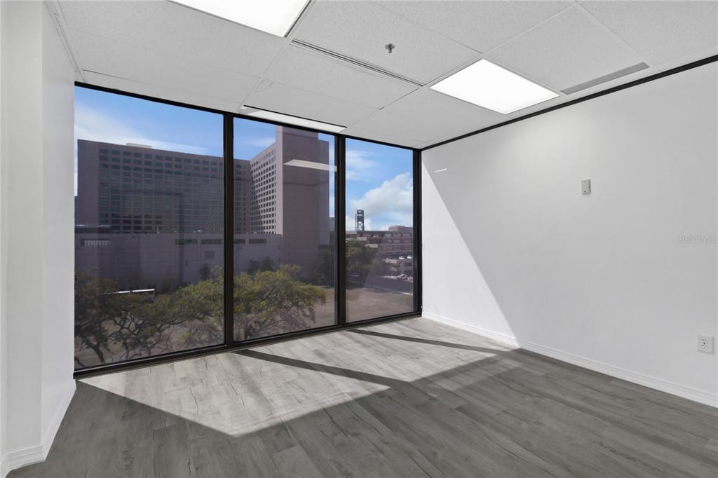 An empty office space features gray wood-look flooring, white walls, and large floor-to-ceiling windows — 233 E BAY STREET UNIT 606, JACKSONVILLE, FL