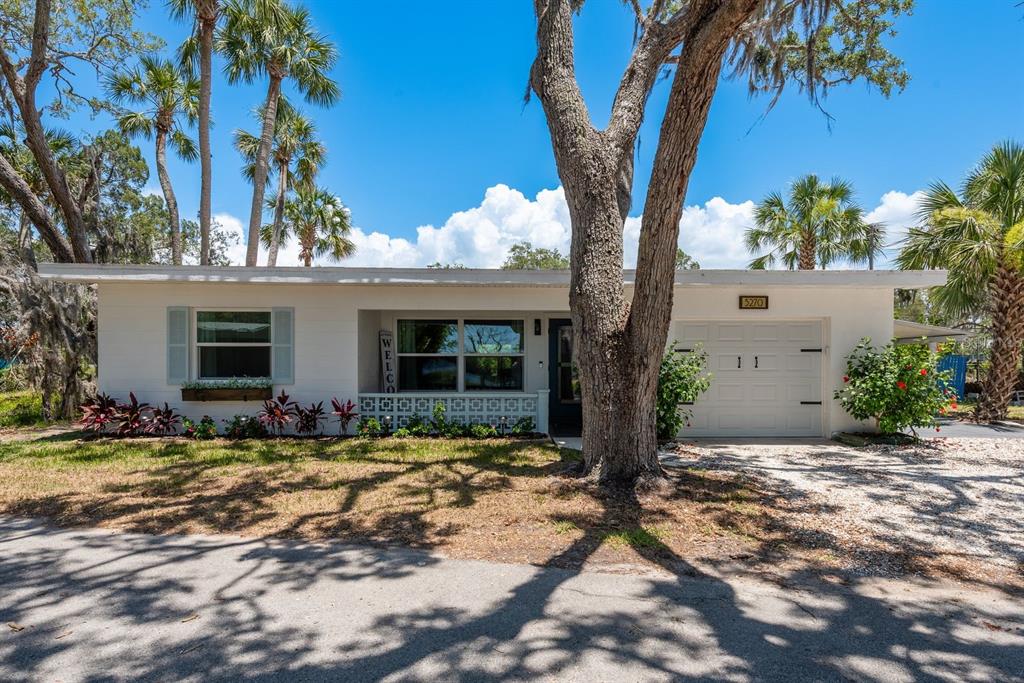 A single-story white house with a garage, a front porch, and palm trees in Florida — 5270 MILLER BAYOU DRIVE, PORT RICHEY, FL