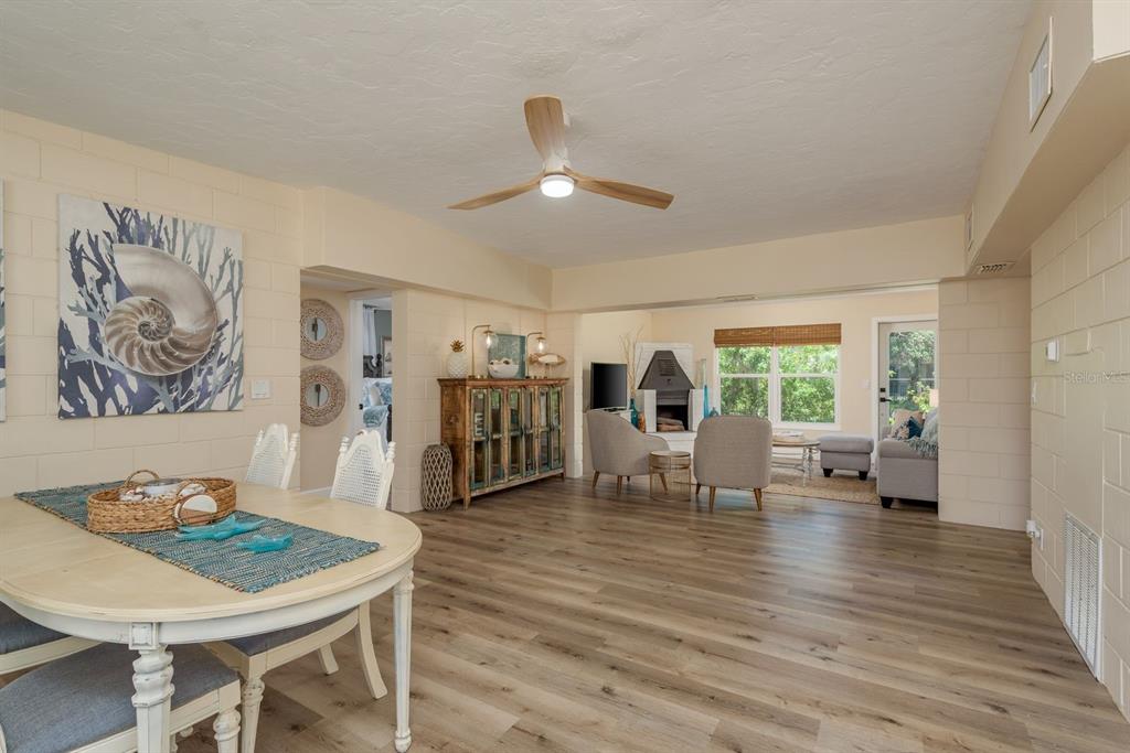 A dining area opens into a living room with light wood flooring and block walls — 5270 MILLER BAYOU DRIVE, PORT RICHEY, FL