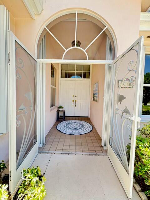 An entryway features double doors, a decorative rug, and two glass storm doors with dolphin designs — 5018 SE Heartleaf Terrace, Hobe Sound FL 33455, HOBE SOUND, FL