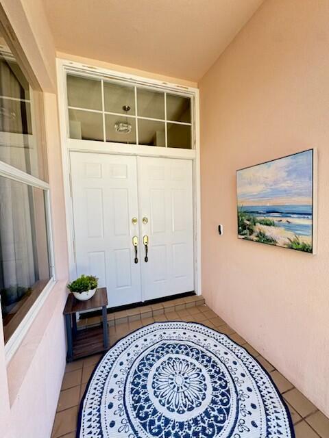 A covered entryway features double white doors, a patterned rug, and a coastal wall painting — 5018 SE Heartleaf Terrace, Hobe Sound FL 33455, HOBE SOUND, FL
