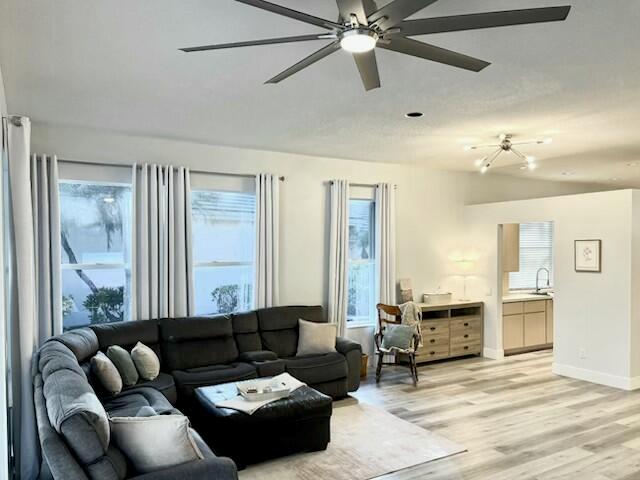 A living room features a dark sectional sofa, a ceiling fan, and light wood flooring — 5018 SE Heartleaf Terrace, Hobe Sound FL 33455, HOBE SOUND, FL