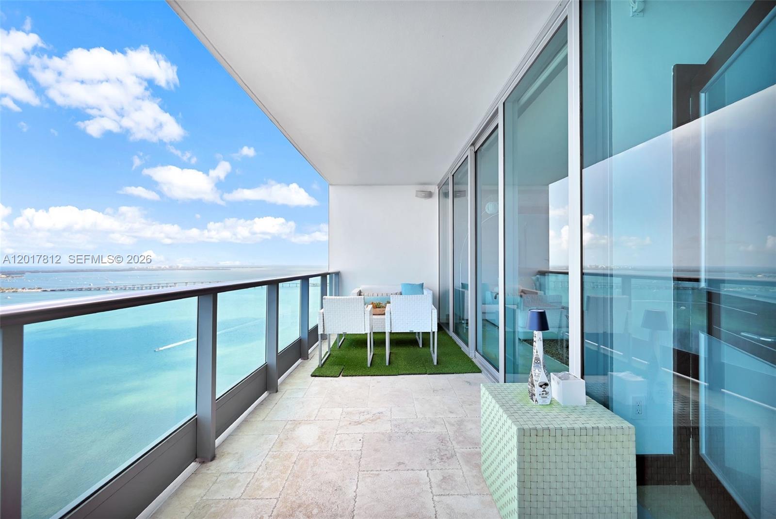 A balcony with stone flooring, outdoor furniture, and a glass railing overlooks the ocean — 1331 Brickell Bay Dr # 3607, Miami FL 33131, MIAMI, FL