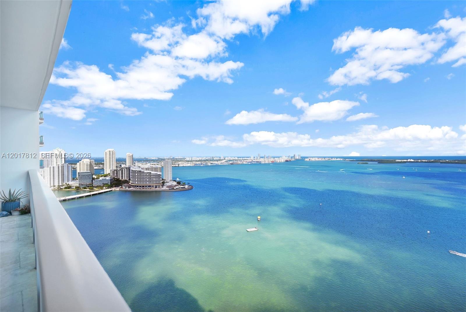 A high-angle view from a balcony overlooking a bay with city buildings in the distance — 1331 Brickell Bay Dr # 3607, Miami FL 33131, MIAMI, FL