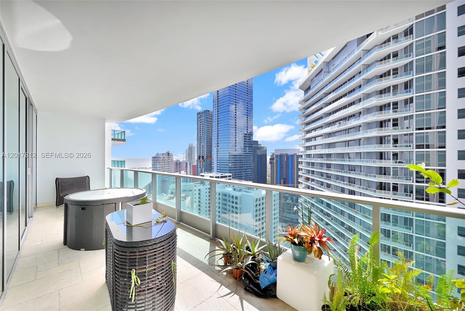 A high-rise balcony features outdoor furniture, potted plants, and a view of surrounding city skyscrapers — 1331 Brickell Bay Dr # 3607, Miami FL 33131, MIAMI, FL