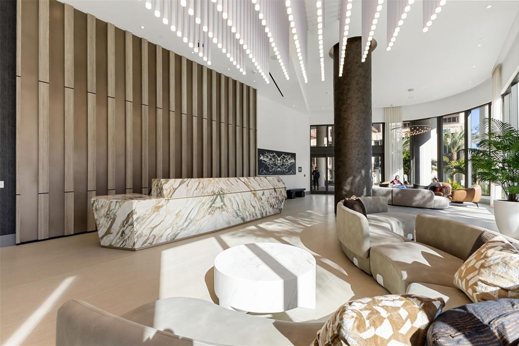 A modern lobby features a marble reception desk, vertical wood paneling, and curved seating areas — 275 1ST AVENUE S UNIT 2308, ST PETERSBURG, FL
