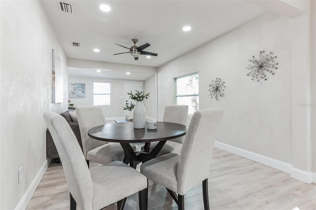 A dining area features a round dark wood table, four upholstered chairs, and light flooring — 3458 QUEENSBORO AVENUE S, ST PETERSBURG, FL
