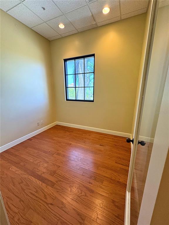 An empty office with light-colored walls, a grid-pane window, and hardwood flooring — 2100 SE HILLMOOR DRIVE UNIT 204A, PORT ST LUCIE, FL