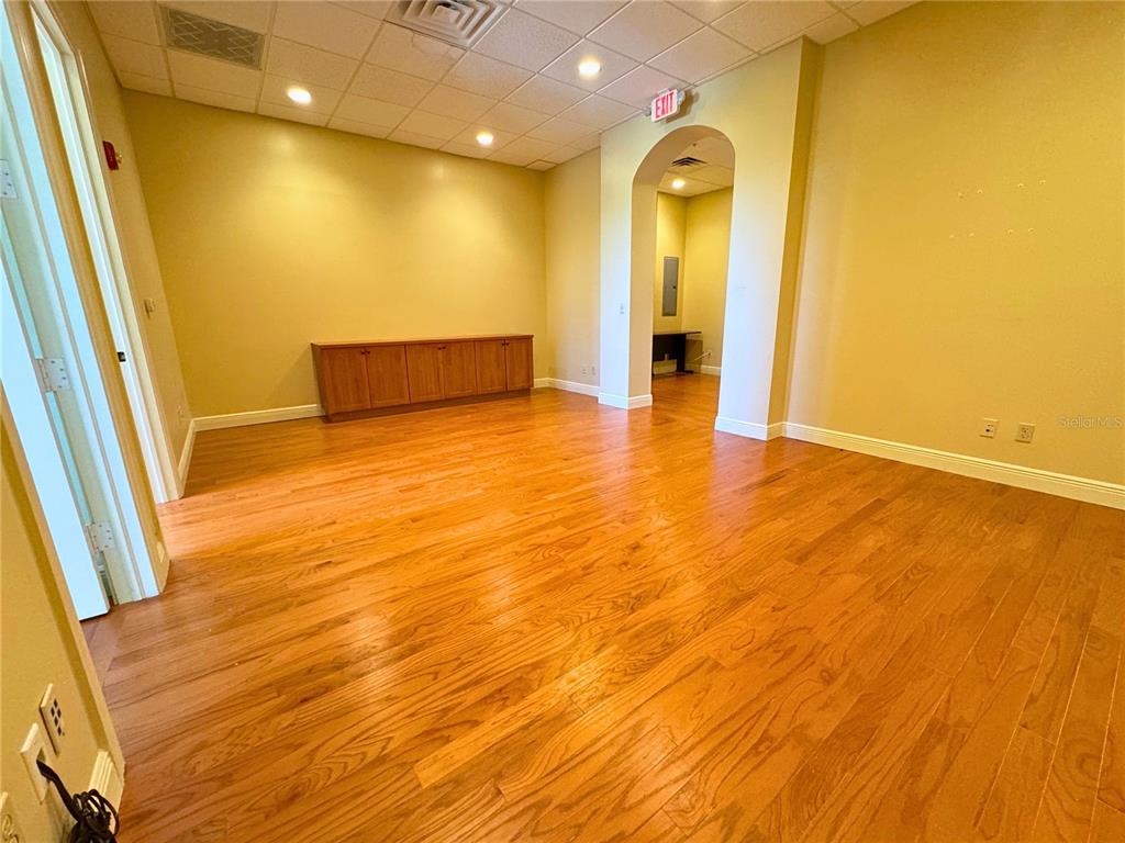 An empty office room features light wood flooring, yellow walls, and a built-in wooden cabinet — 2100 SE HILLMOOR DRIVE UNIT 204A, PORT ST LUCIE, FL