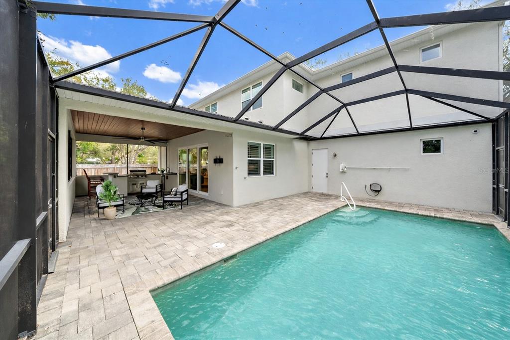 A screened-in patio features a swimming pool, paved deck, and an outdoor kitchen area — 2207 WISTERIA STREET, SARASOTA, FL