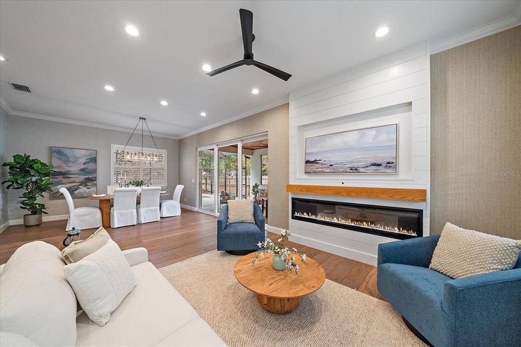 A living room features a linear fireplace, shiplap wall, blue armchairs, and an adjacent dining area — 2207 WISTERIA STREET, SARASOTA, FL