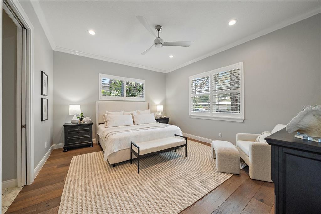 A bedroom features a bed, a bench, an armchair with ottoman, and hardwood floors — 2207 WISTERIA STREET, SARASOTA, FL