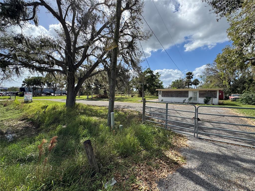 A gravel driveway leads to a small, single-story building behind a metal gate — 2739 TAYLOR ROAD, PUNTA GORDA, FL