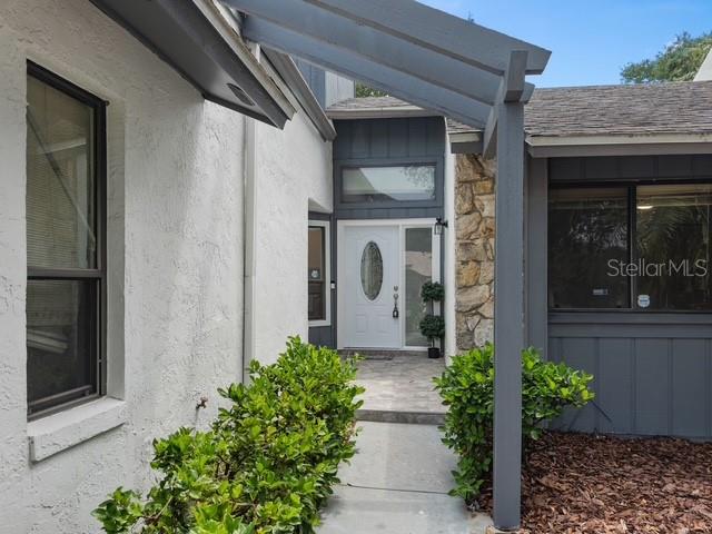 The exterior view shows a white stucco house with a gray pergola over the entryway — 1033 OLD SOUTH LANE, APOPKA, FL