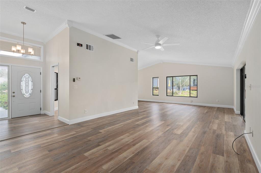 A bright, open-concept living area features light-colored walls, wood-look flooring, and a ceiling fan — 1033 OLD SOUTH LANE, APOPKA, FL