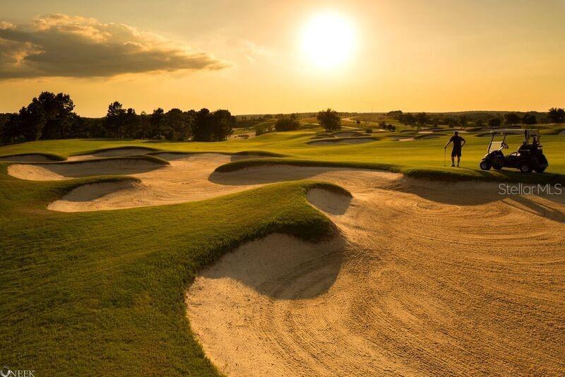 A golfer stands near a golf cart on a sand bunker at a golf course — 15910 VETTA DRIVE, BELLA COLLINA, FL