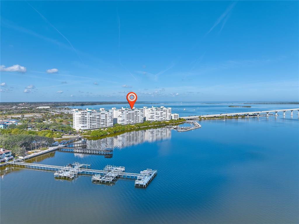 An aerial view shows a large waterfront apartment complex with docks extending into the bay — 5 INDIAN RIVER AVENUE UNIT 1204, TITUSVILLE, FL