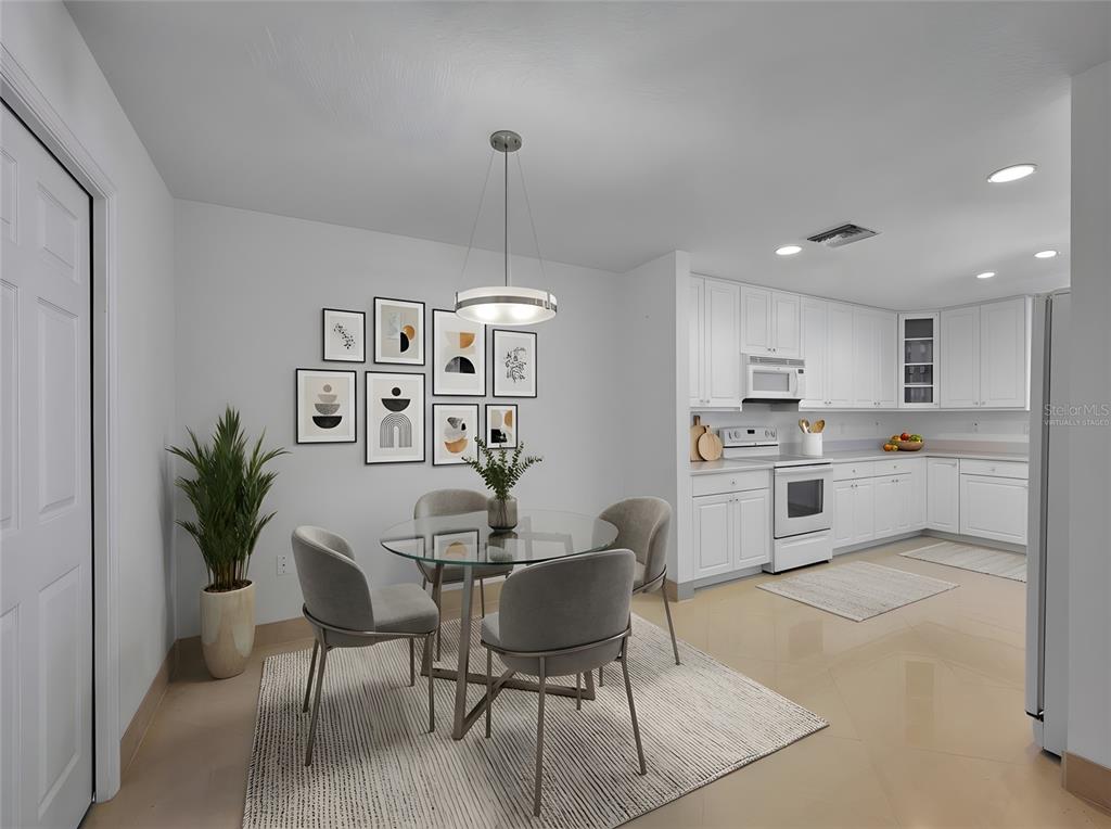 A dining area with a glass table and chairs sits adjacent to a white kitchen — 5 INDIAN RIVER AVENUE UNIT 1204, TITUSVILLE, FL