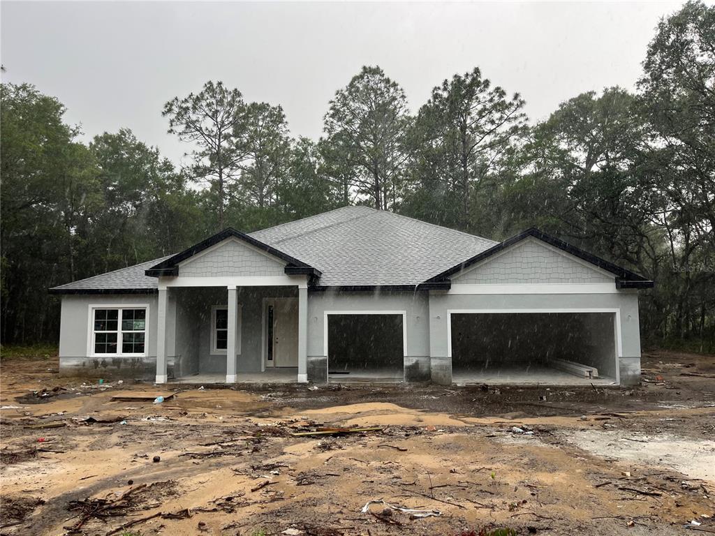 A newly constructed single-story house with a two-car garage sits on a dirt lot — 12 S SCHOOL AVENUE, LECANTO, FL