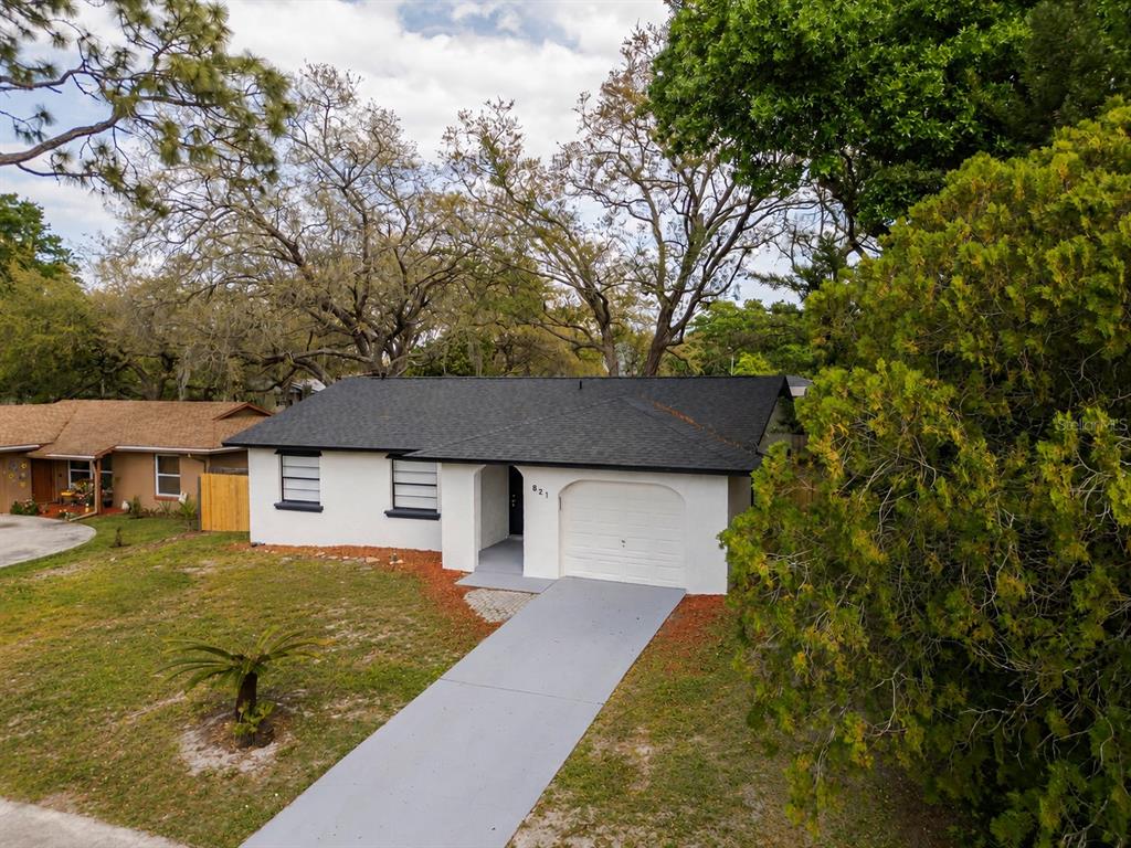 An exterior view of a white single-story house with a black roof and attached garage — 821 OSCEOLA TRAIL, CASSELBERRY, FL