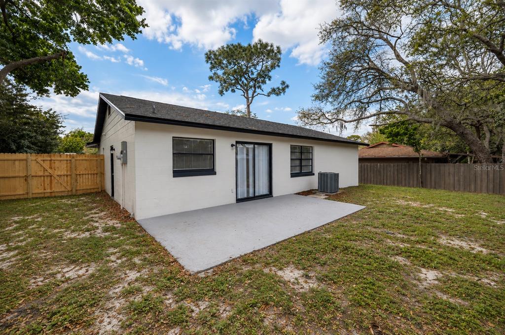 The exterior of a white house features a concrete patio, sliding glass doors, and fencing — 821 OSCEOLA TRAIL, CASSELBERRY, FL
