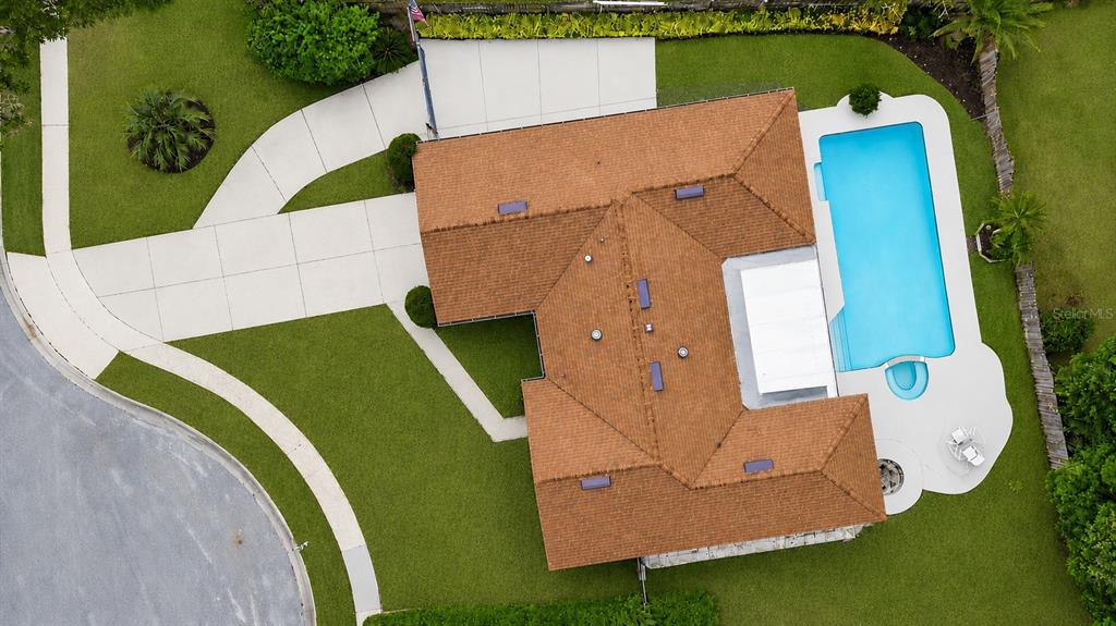 An aerial view shows a house with a brown roof, a pool, and a driveway — 102 ASPEN PLACE, LONGWOOD, FL