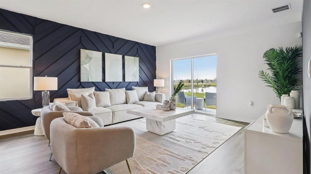 A living room features a dark blue geometric accent wall, a sectional sofa, and sliding doors — 4078 LIMEKLIN FALLS LOOP, DAVENPORT, FL