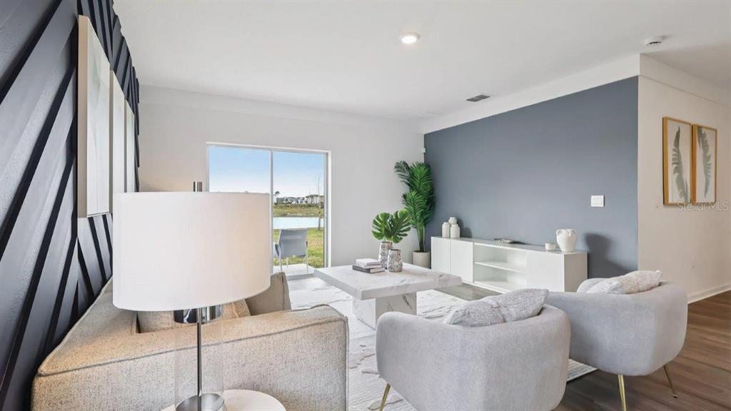 A living room features a blue accent wall, marble coffee table, and sliding glass doors — 4078 LIMEKLIN FALLS LOOP, DAVENPORT, FL