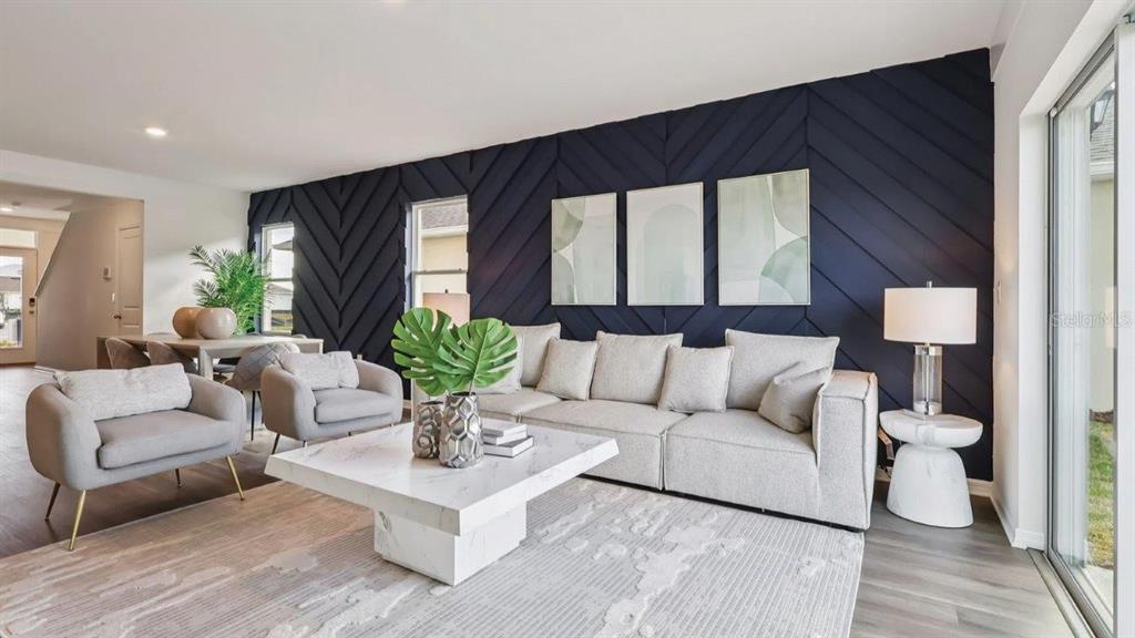A living room features a dark blue chevron-patterned accent wall, light furniture, and marble table — 4078 LIMEKLIN FALLS LOOP, DAVENPORT, FL