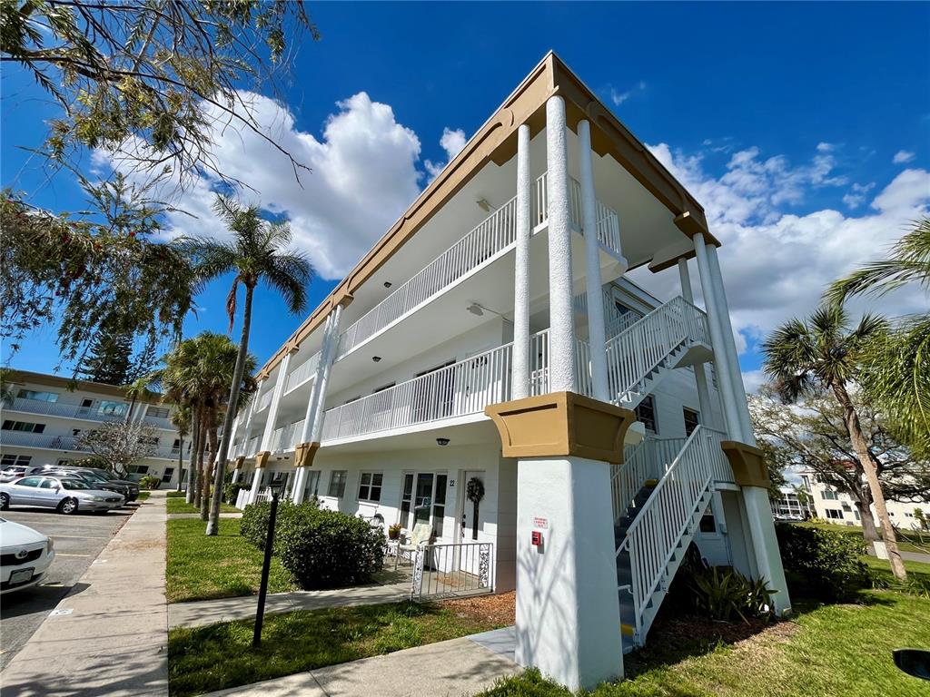 A three-story apartment building with white exterior walls, balconies, and an outdoor staircase — 2430 BRAZILIA DRIVE UNIT 44, CLEARWATER, FL