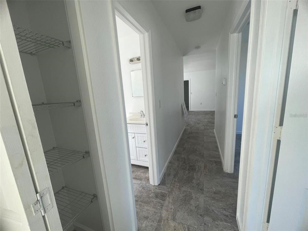 A hallway with gray tile flooring leads to a bathroom and an adjacent room — 525 E HELEN AVENUE, PUNTA GORDA, FL
