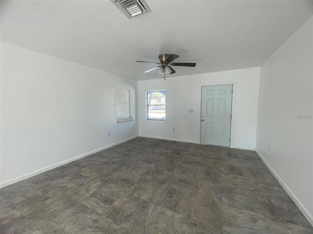 An empty room features white walls, a ceiling fan, and gray tile flooring — 525 E HELEN AVENUE, PUNTA GORDA, FL