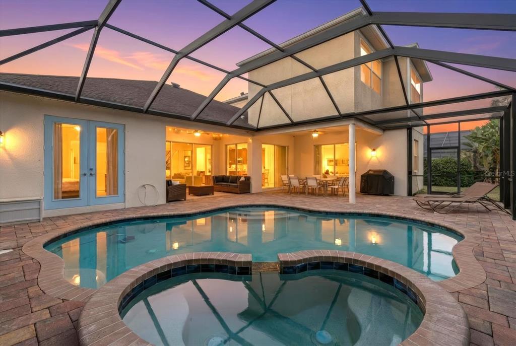 A screened-in pool and spa area with a patio and view of the house exterior — 4727 BALBOA PARK LOOP, BRADENTON, FL