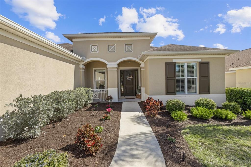 A beige single-story house features a concrete walkway leading to a recessed front entryway — 4727 BALBOA PARK LOOP, BRADENTON, FL