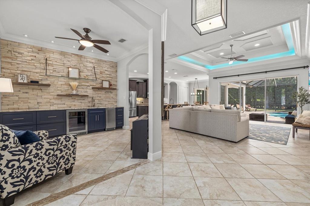 A living room and wet bar area with stone wall accents, tile floors, and pool views — 4727 BALBOA PARK LOOP, BRADENTON, FL