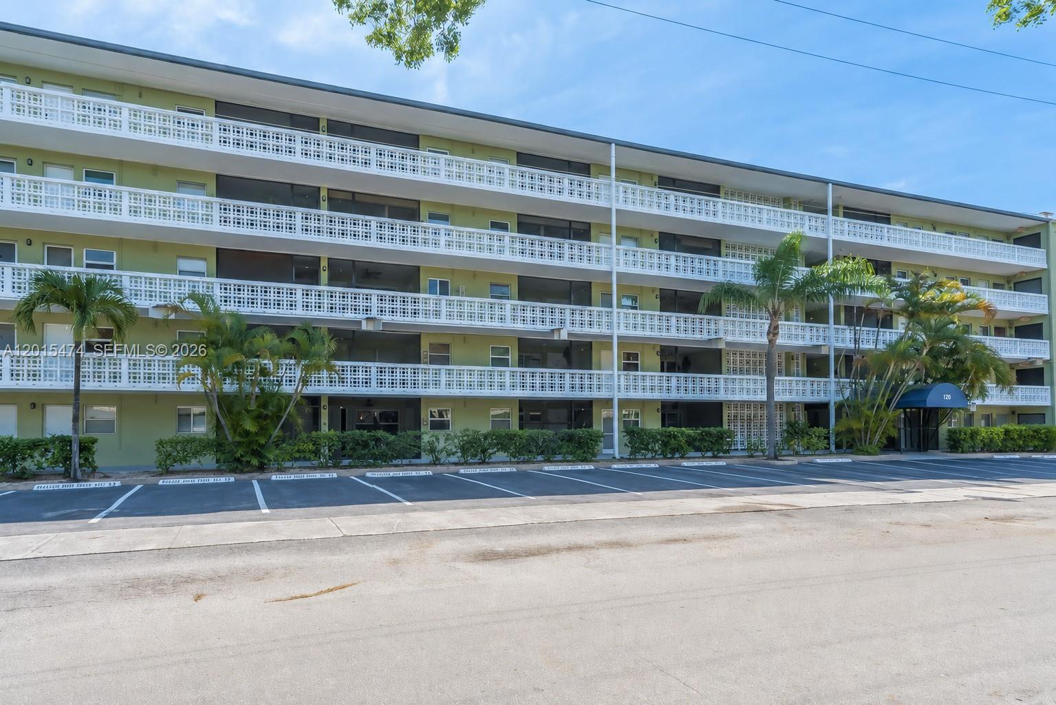 A multi-story apartment building features white balconies and a parking lot in the foreground — 1425 Arthur St # 103A, Hollywood FL 33020, HOLLYWOOD, FL