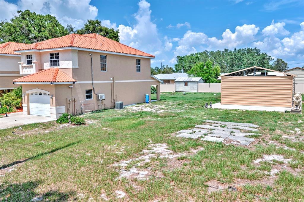 A two-story house with a tile roof stands next to a detached metal storage shed — 4050 PLACID LAKES BOULEVARD, LAKE PLACID, FL