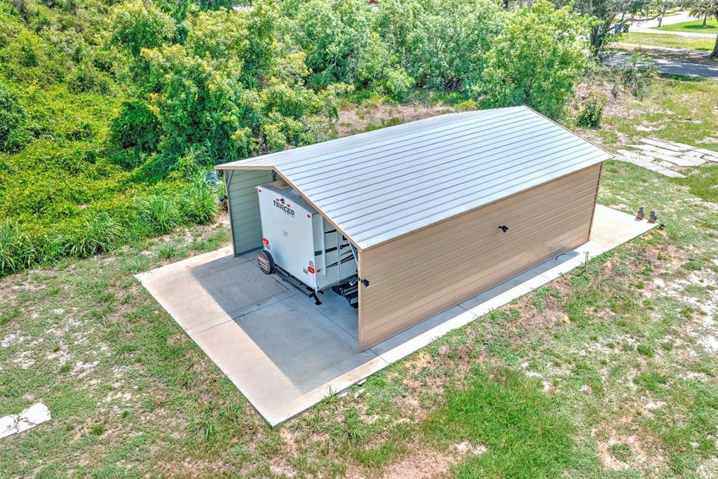 An aerial view shows a metal carport sheltering a travel trailer on a concrete slab — 4050 PLACID LAKES BOULEVARD, LAKE PLACID, FL