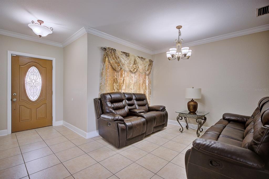 A living room features tile flooring, two brown leather recliners, and a glass-topped side table — 4050 PLACID LAKES BOULEVARD, LAKE PLACID, FL
