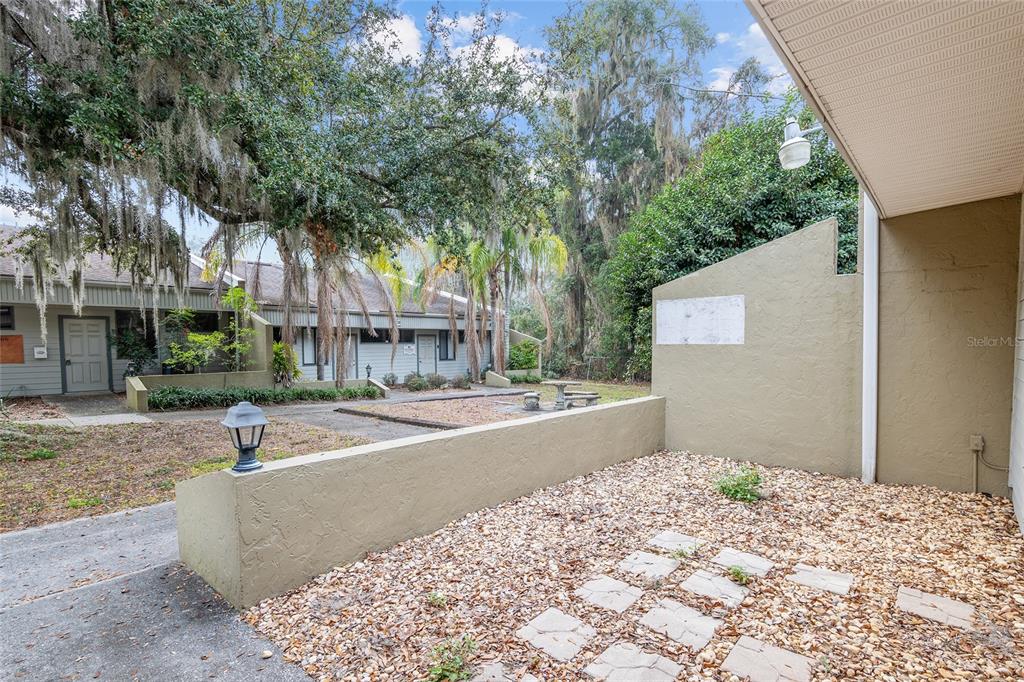 A small gravel patio with stone pavers is enclosed by a low stucco wall — 2801 SW COLLEGE ROAD UNIT 24, OCALA, FL