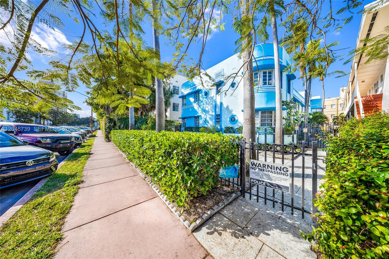 A blue Art Deco building stands behind a hedge and a metal gate on a sidewalk — 1250 Drexel Ave # 8, Miami Beach FL 33139, MIAMI BEACH, FL